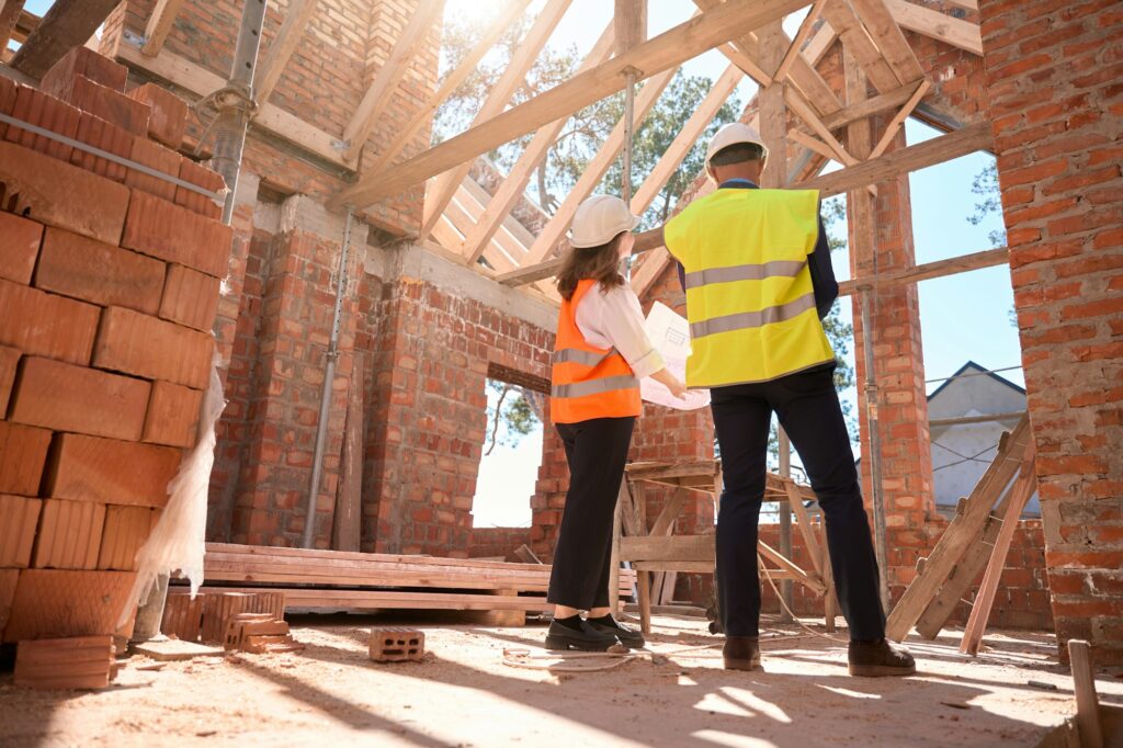 General foreman and female architect holding building blueprint