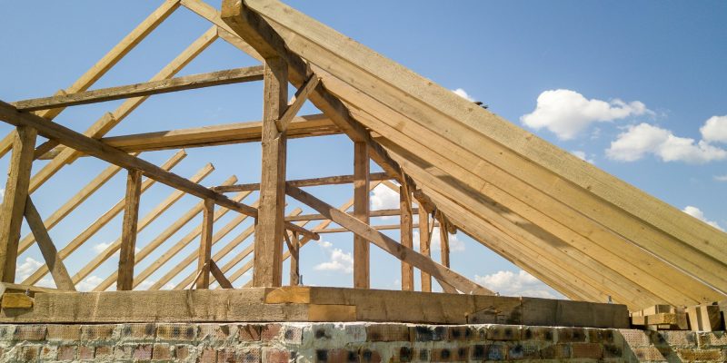 Aerial view of unfinished house with wooden roof frame structure under construction